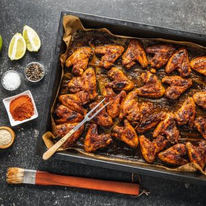 Grilled chicken wings in barbecue sauce in baking tray.